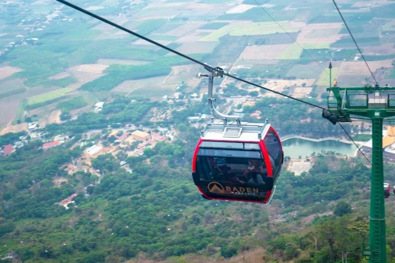 Một chiếc taxi Mai Linh đậu gần khu vực ga cáp treo hoặc bãi đậu xe dưới chân Núi Bà Đen ở Tây Ninh, có hình ảnh núi phía sau.